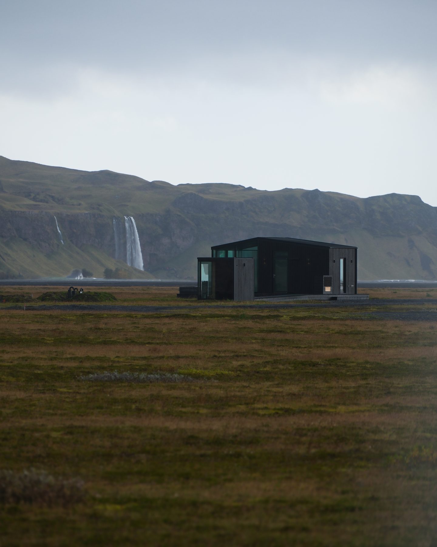 Harmony lodge on the South Iceland plain with Seljalandsfoss waterfall on the cliffs behind