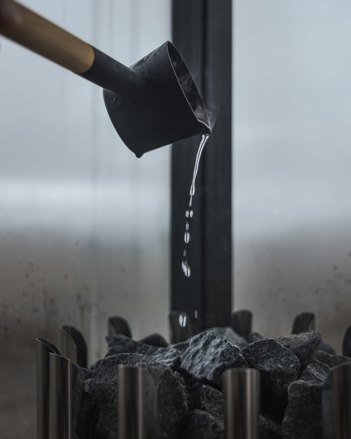 Wooden ladle pouring water over hot sauna stones, private sauna at Harmony Seljalandsfoss Iceland