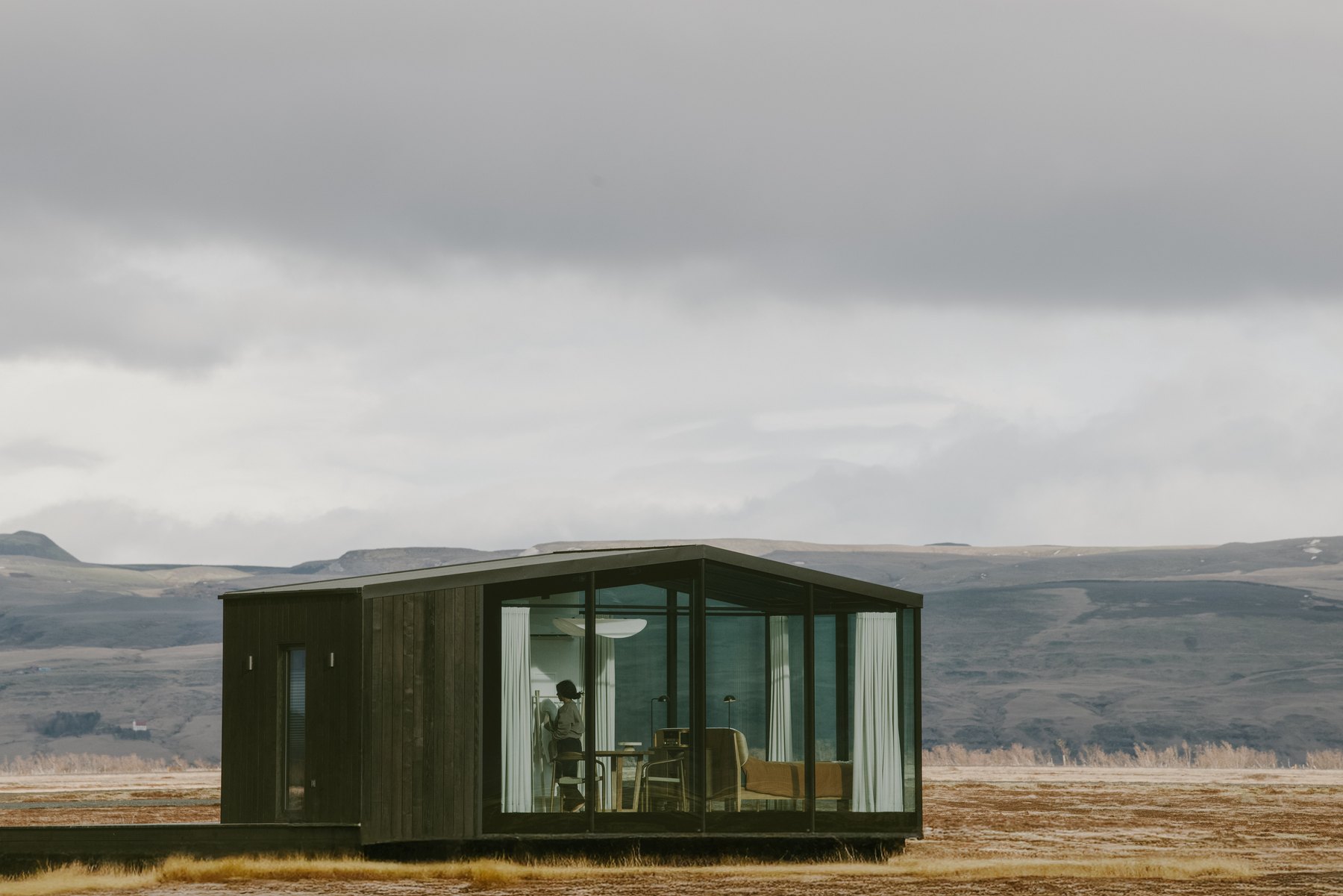 Harmony Seljalandsfoss glass lodge as a low dark form in the wide South Iceland landscape