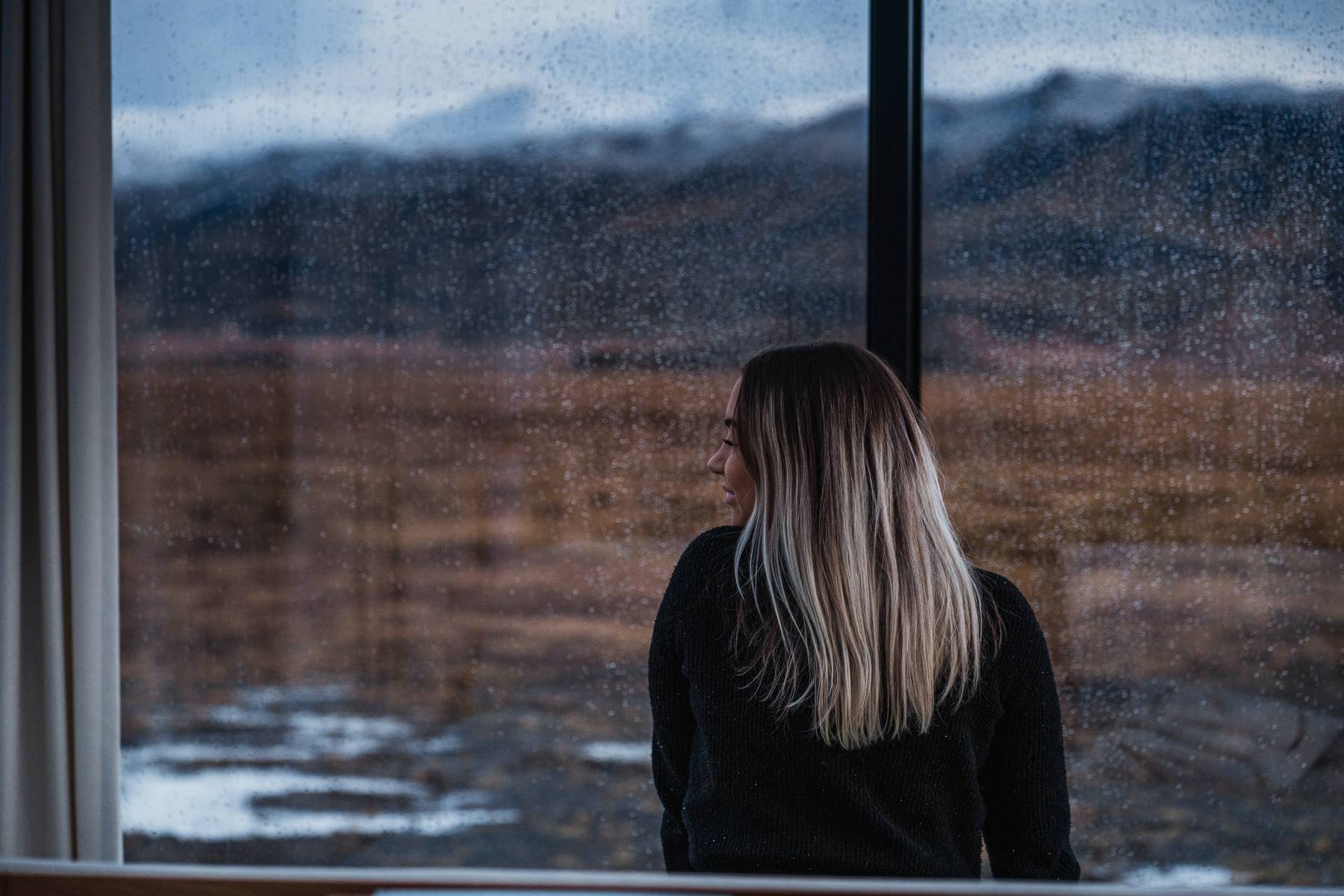 Rainy autumn day seen through the glass wall of a luxury cabin in Iceland with misty mountains