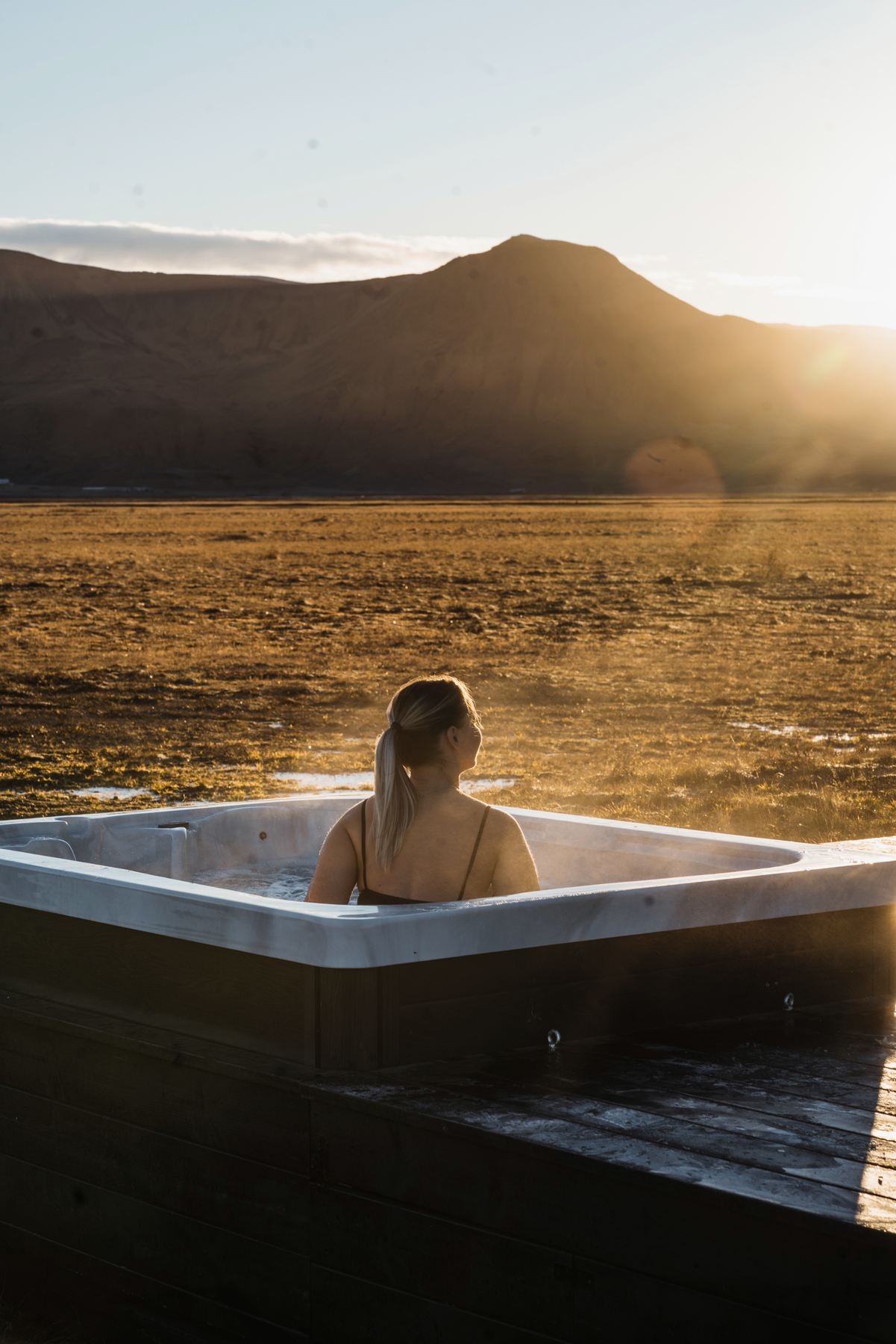 Guest relaxing in a private hot tub in golden autumn light at a luxury lodge in Iceland