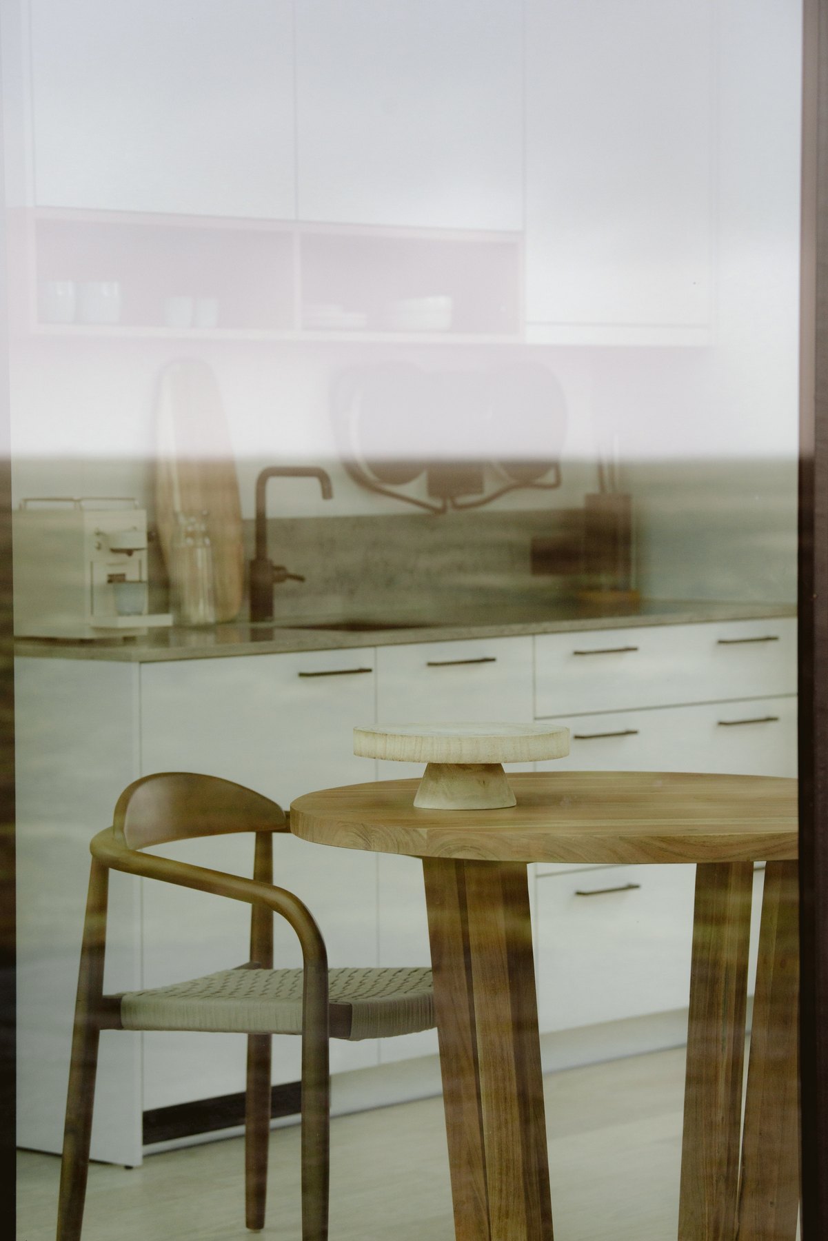 Minimalist interior of the glass lodge with kitchenette and timber table seen through the glazing